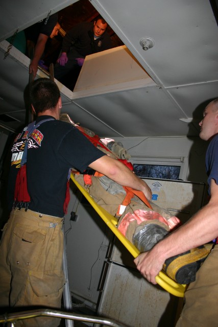 Justin Sosebee, Peter Nash, and Jonathon McKee assist in lowering a patient from the attic during Training/House Burn Nov 12, 2006 Transco Road