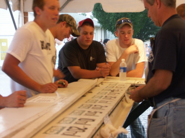 Fair goers try their luck at the Money Wheel as Tim Titcomb oversees their play.