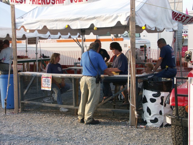 Debbie S. Saunders, Debbie H. Saunders, Frank Saunders working the Nevada stand, while Sandy Saunders, and John Mills chat about the day's events.