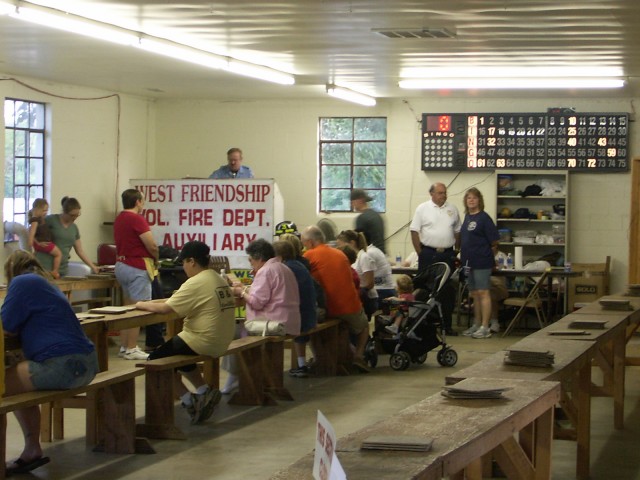 Keith Beck calling numbers during the Bingo game. Shirley Mills assisting Bingo players. John and Diana Coll discuss the afternoon events.
